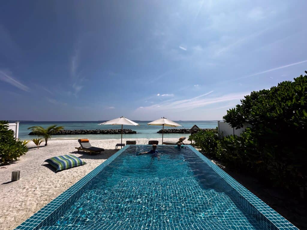 Boys swim in pool on beachfront at Emerald Faarufushi Resort in the Maldives.