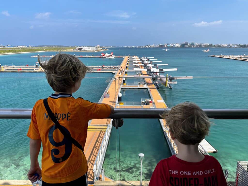 Two boys look from balcony down to water at the seaplane terminal at Male airport in the Maldives.