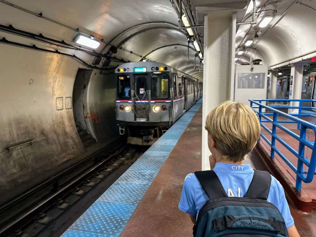 Boy in underground train station in Chicago. Train approaching on the left.