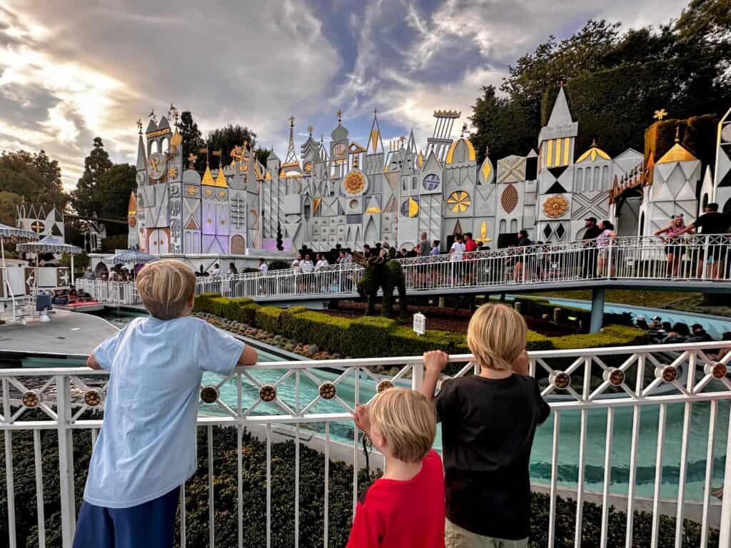 Three boys look at the ride 'It's a Small World' at dusk at Disneyland in California.