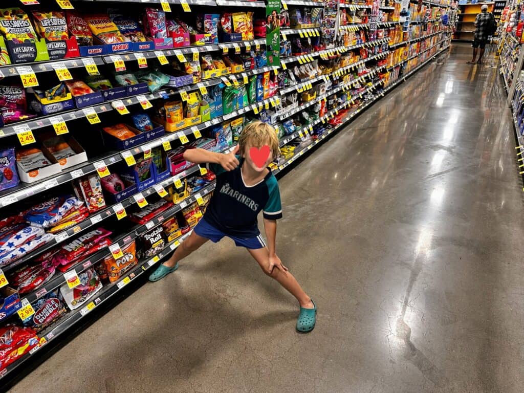 Boy stands in a grocery store aisle (the candy section) in Phoenix, Arizona. He's giving a thumbs up.