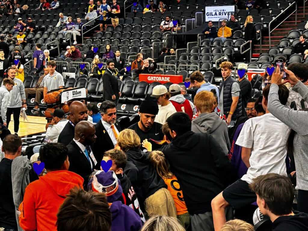 Devin Booker of the Phoenix Suns signs autographs for kids in the stands following his pregame warmup.