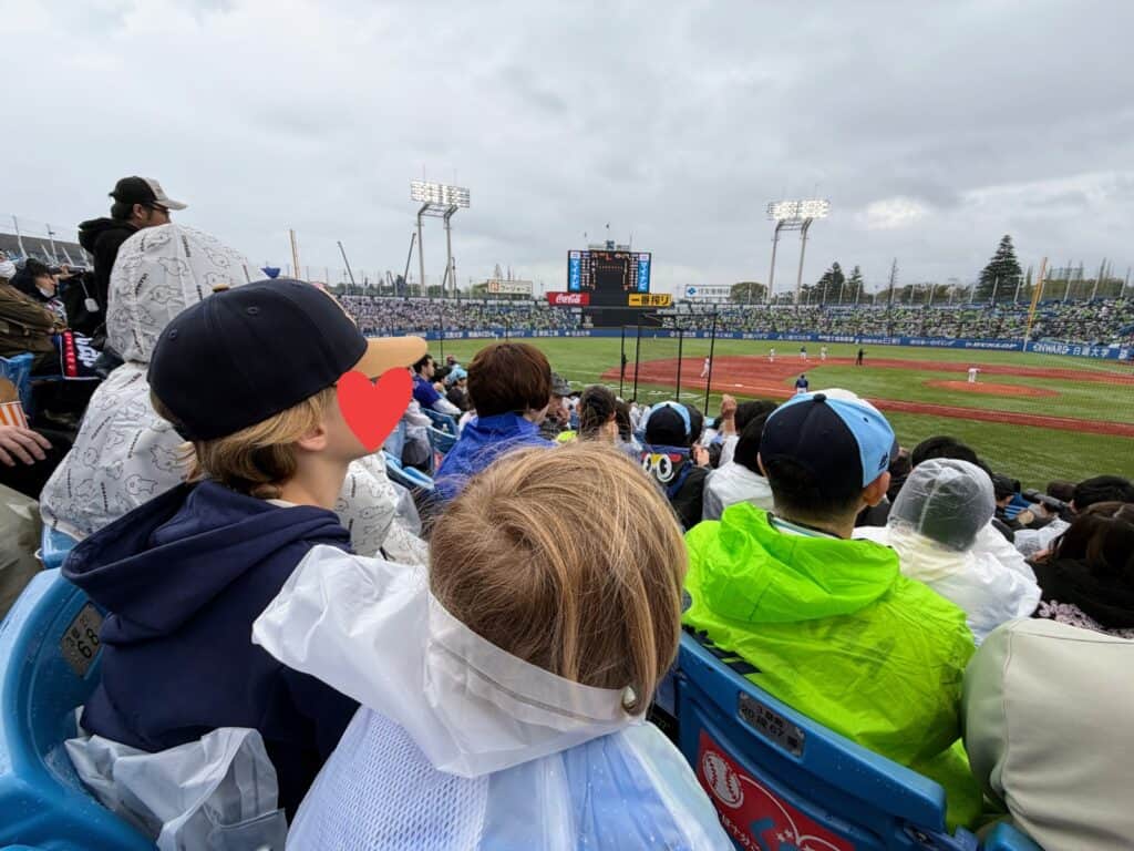 Two boys watch baseball game in Tokyo on a rainy day.
