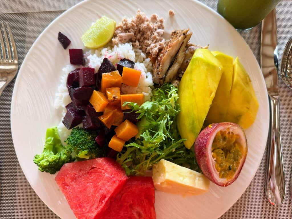 Breakfast plate in the Maldives with mango, passionfruit, watermelon, roasted vegetables, rice, mashuni, and fish.