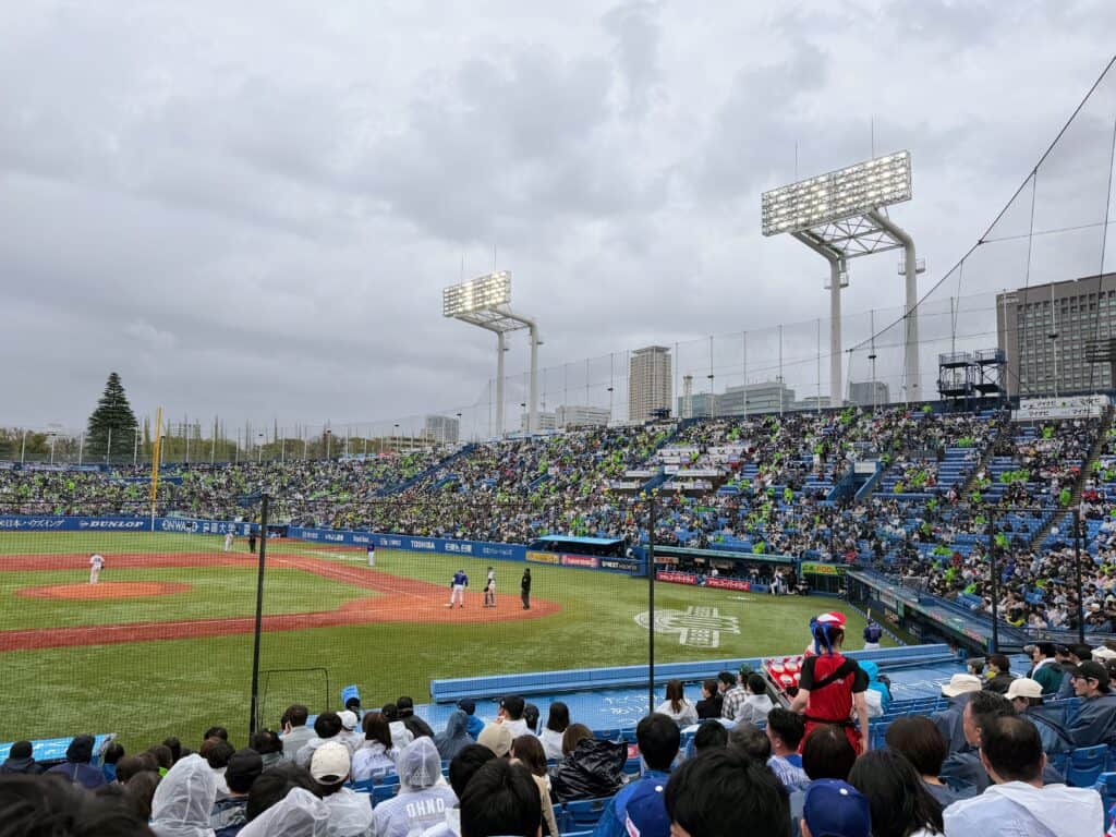 Cloudy day at Meiji Jingu stadium in Tokyo. Batter ready to hit. Stands are mostly full.