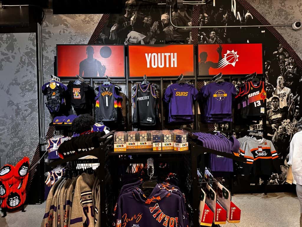 Youth merchandise section in the Phoenix Suns team store in Phoenix, Arizona. T-shirts, jerseys, and more for sale on racks and shelves.