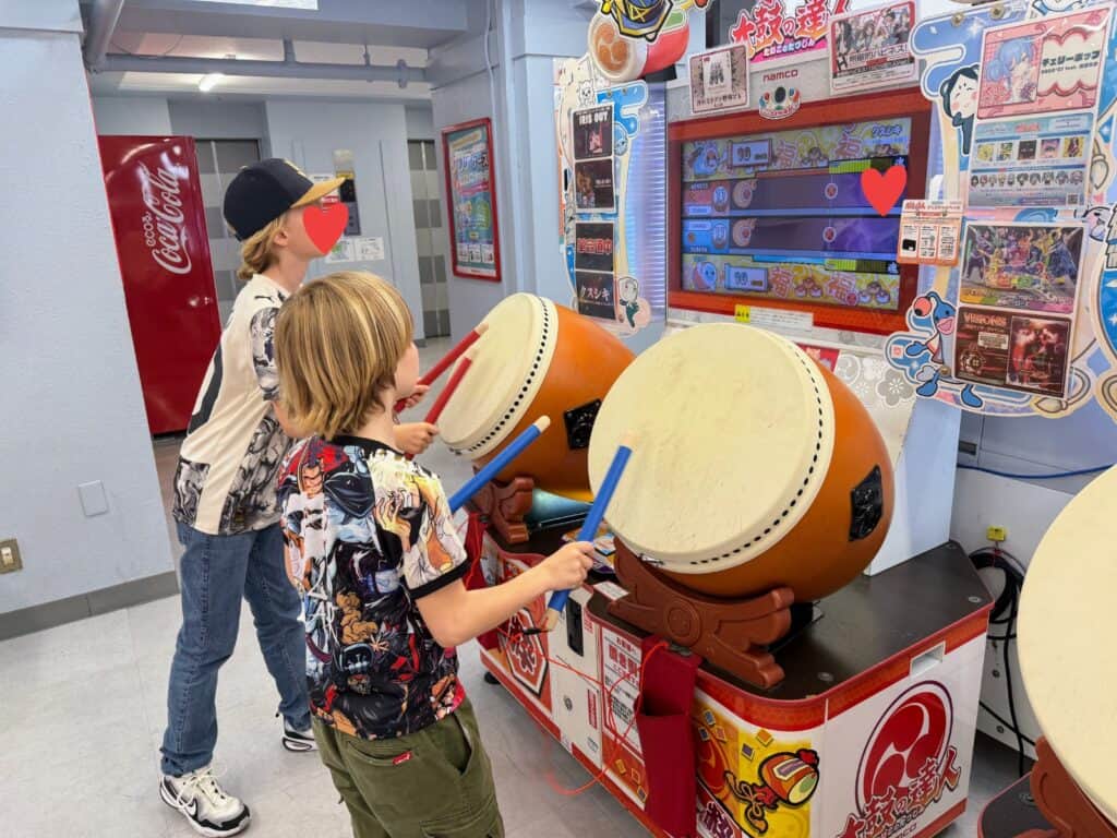 Two boys play large drum video game inside an arcade in Tokyo, Japan.
