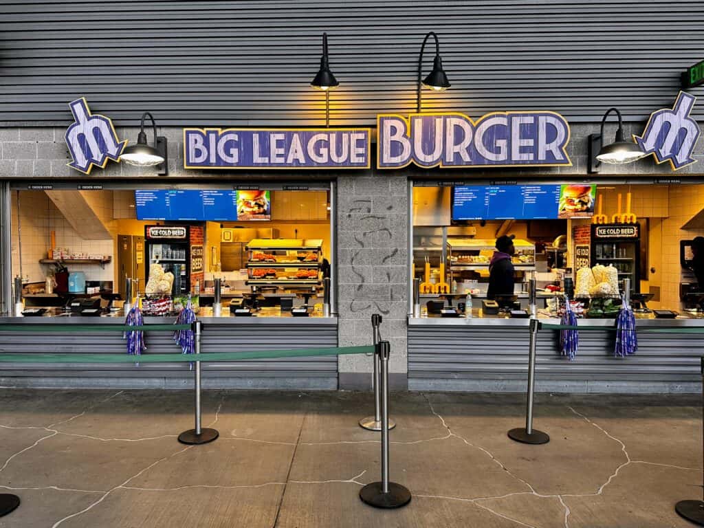 No lines in front of Big League Burger, a concessions stand at Seattle Mariners baseball stadium. Food on display and drinks in refrigerators.